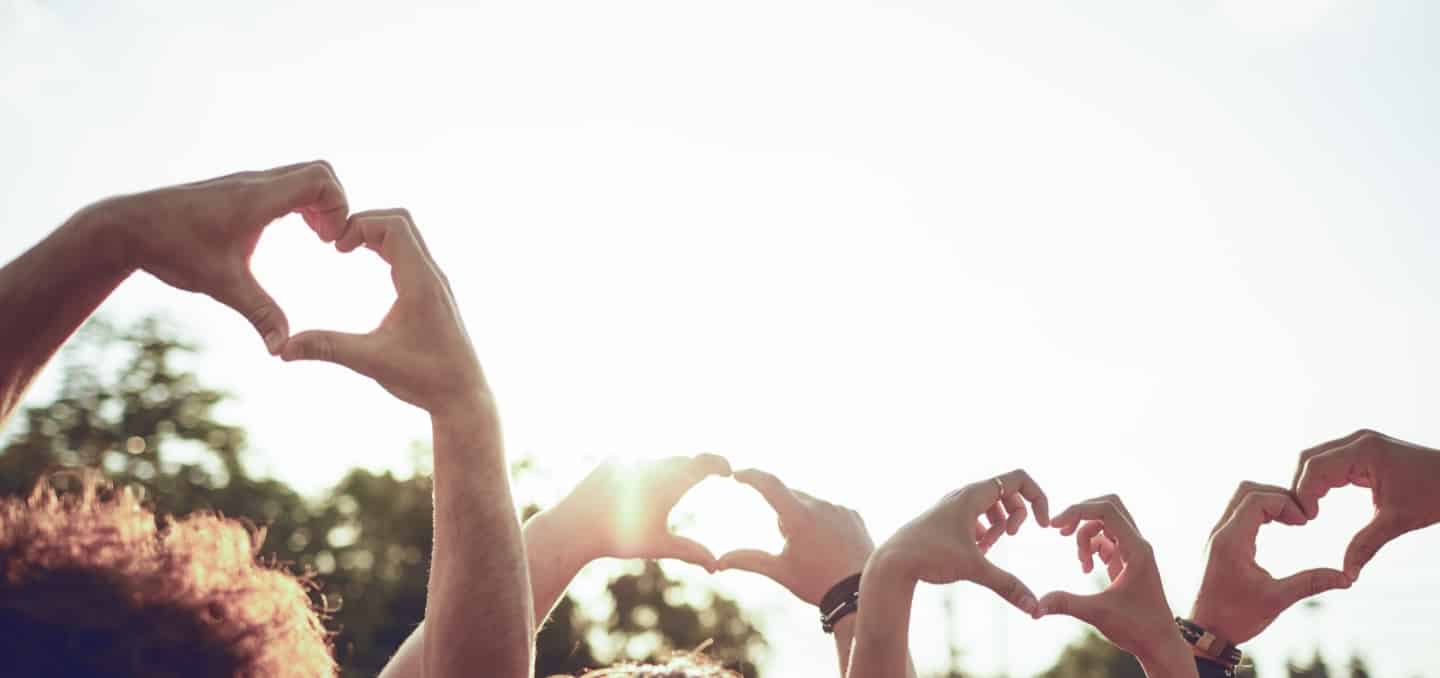 People outdoors making hearts with their hands